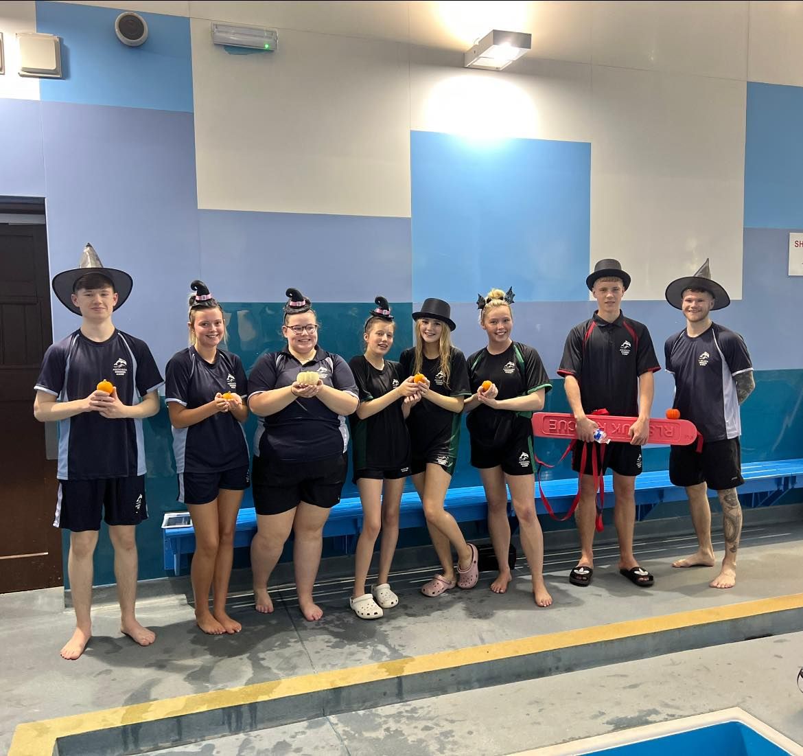Academy staff in costume with hats and inflatable horses beside the pool